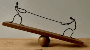 Stick figures having a tug of war on a seesaw.